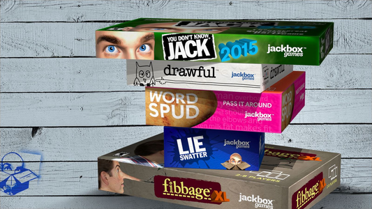 Stack of Jackbox party game boxes balanced vertically against a light wooden wall background, featuring titles like You Don’t Know Jack, Drawful, Word Spud, Lie Swatter, and Fibbage XL.