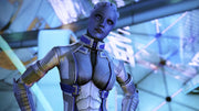 Close-up of a blue-skinned Asari character from Mass Effect: Andromeda wearing futuristic armor, standing inside a sleek sci-fi facility with bright, geometric lighting in the background.