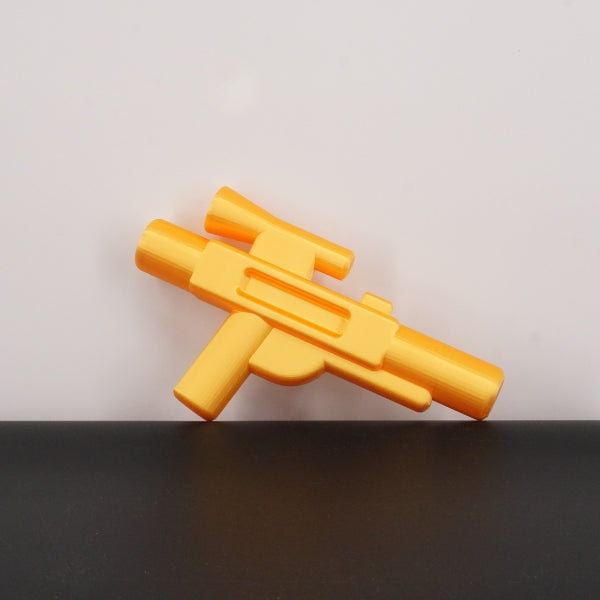 Yellow brick style blaster replica inspired by classic block building toys, 3D printed prop displayed on a table.