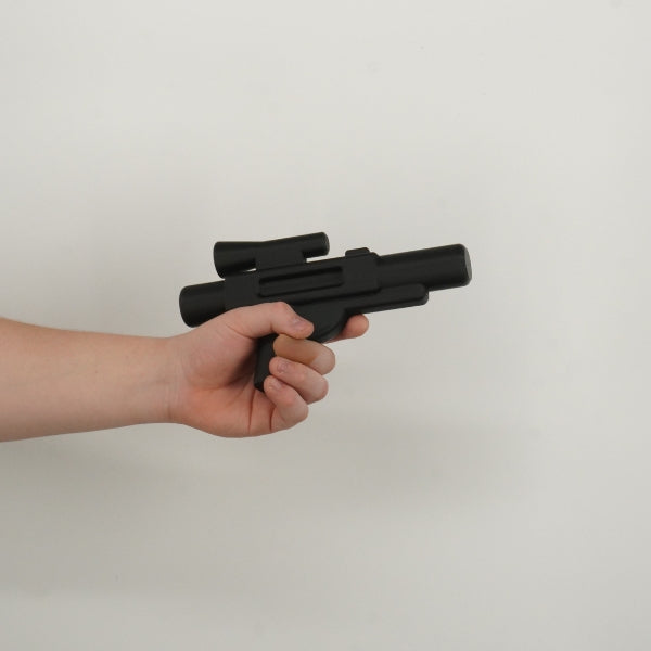 Black brick style blaster replica held in hand showing life size scale of the 3D printed prop.