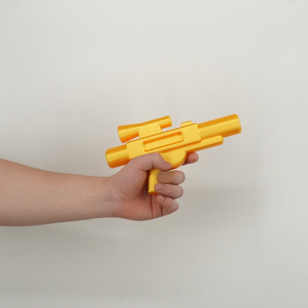 Yellow brick style blaster replica held in hand demonstrating the size of the 3D printed toy inspired prop.