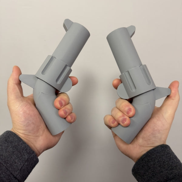 Two gray brick style revolver replicas held in both hands showing the life size 3D printed props.