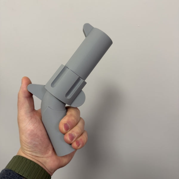 Gray brick style revolver replica held in hand showing the size of the 3D printed prop.