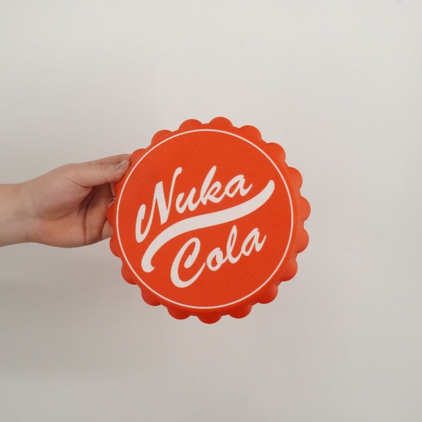 Nuka Cola bottle cap wall hook replica inspired by Fallout held in hand showing the size of the 3D printed wall decor prop.
